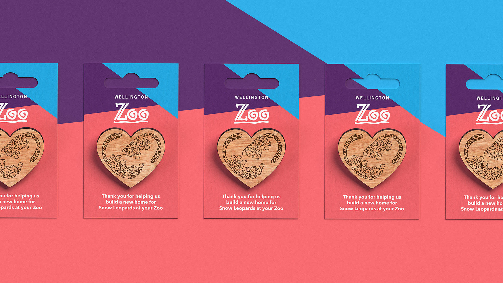The snow leopard pins for Wellington Zoo, displayed on a coral pink and blue background, designed by Bradley Pratt